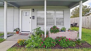 A house with a porch, a front door, and a small garden with flowers and plants.