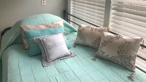 A bed with a light blue quilt and several decorative pillows, including one with the word "DREAM" on it.