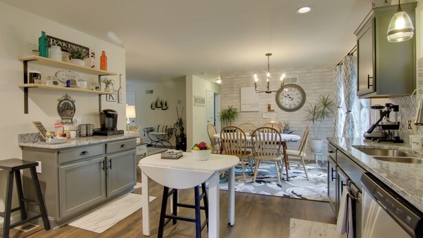A modern kitchen with grey cabinets, a white countertop, and a dining area with a white table and chairs. - Ocean View Escape ~ 4 Miles to Bethany Beach! (Ocean View)