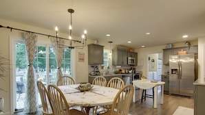 A modern kitchen with a dining area, featuring a central island, wooden chairs, and a chandelier. - Ocean View Escape ~ 4 Miles to Bethany Beach! (Ocean View)