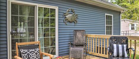 A deck with two chairs, one with a patterned cushion and another with a striped cushion, and a potted plant.