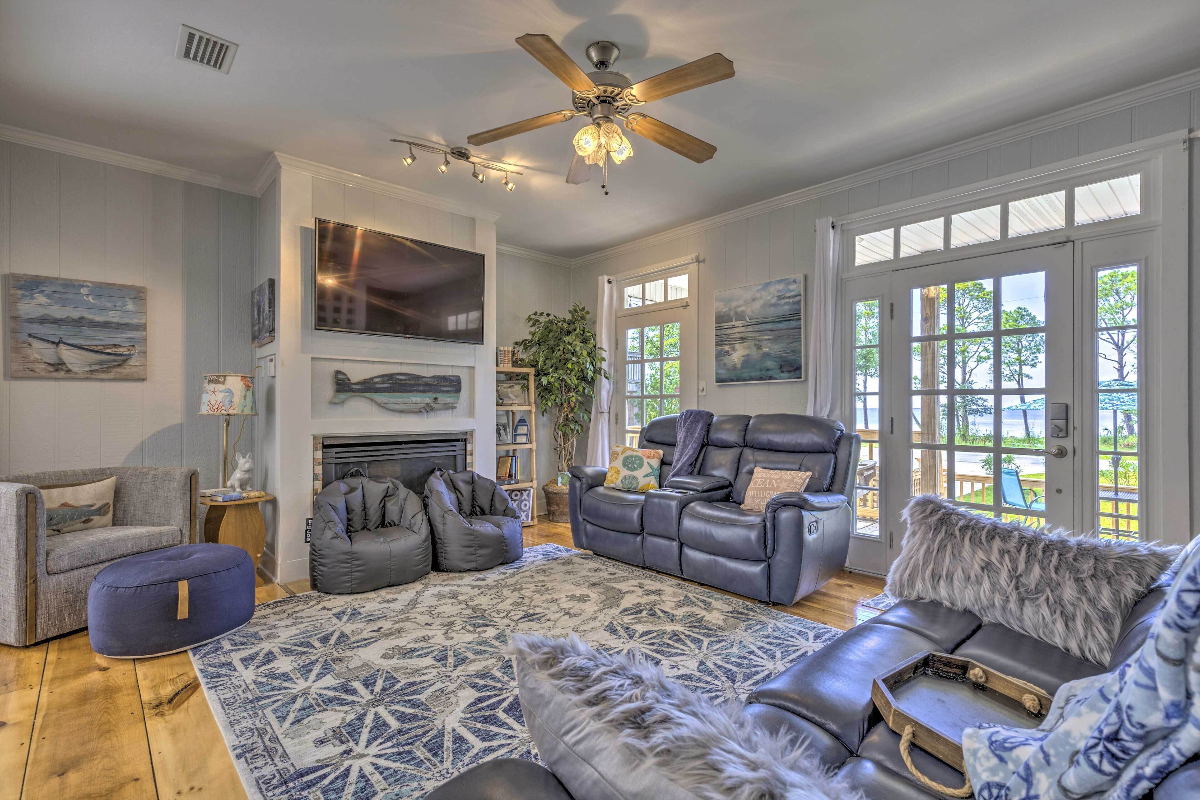 A spacious living room with a fireplace, leather sofas, and a large window providing a view of the outdoors.