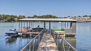 A dock with a covered seating area, a jet ski, and a boat. - Boat Dock, Furnished Deck! Lakefront Ozarks Home (Lake Ozark)