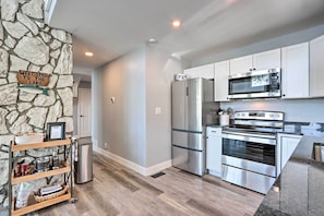 A modern kitchen with stainless steel appliances, a stone accent wall, and a welcome sign.