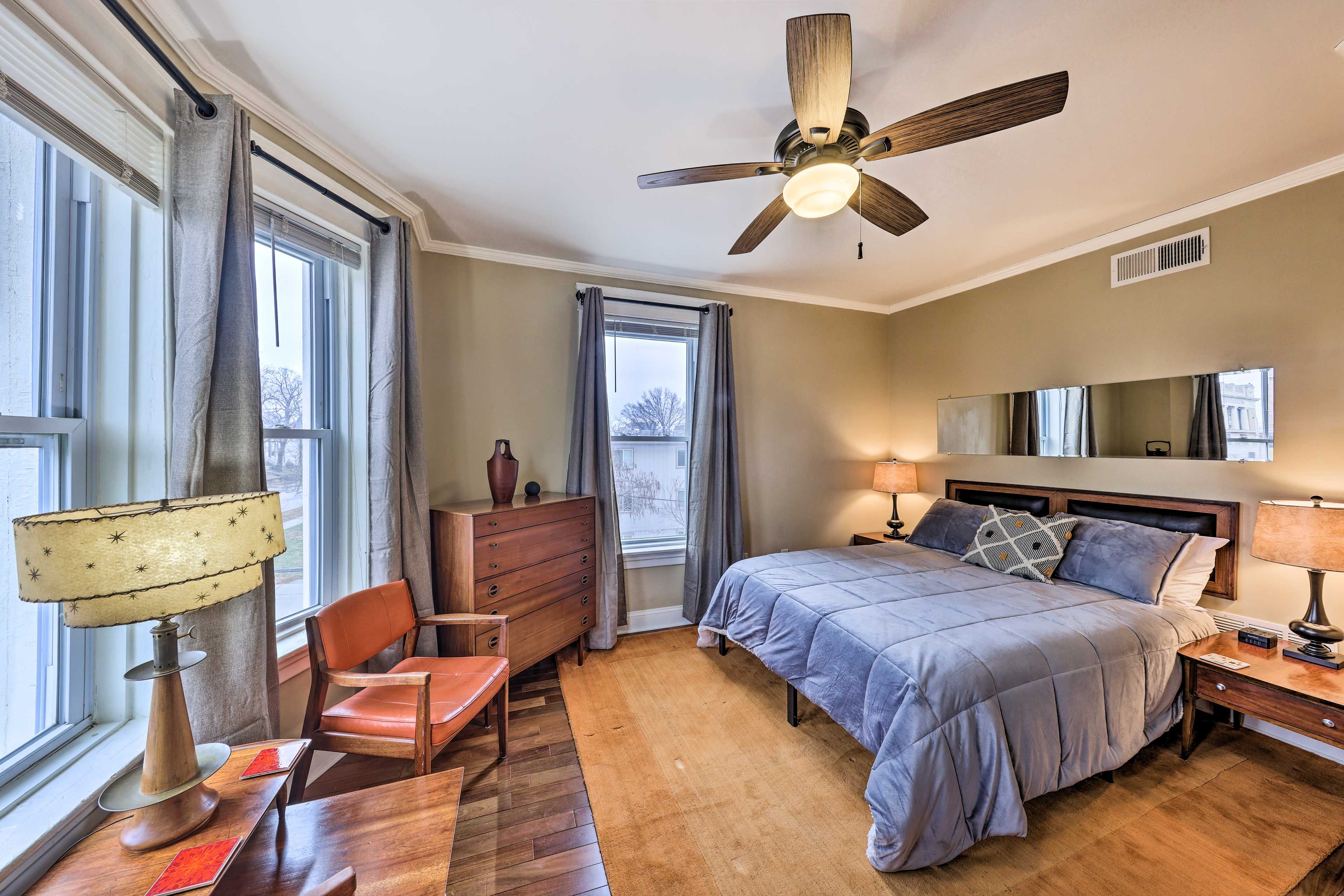 A bedroom with a bed, a desk, a chair, a dresser, and a ceiling fan.