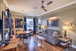 A modern living room with a sofa, coffee table, dining table, and chairs. There is a ceiling fan, a lamp, and a painting on the wall. - Walkable KC Home Base! Near Sports Events & Fun (Kansas City)
