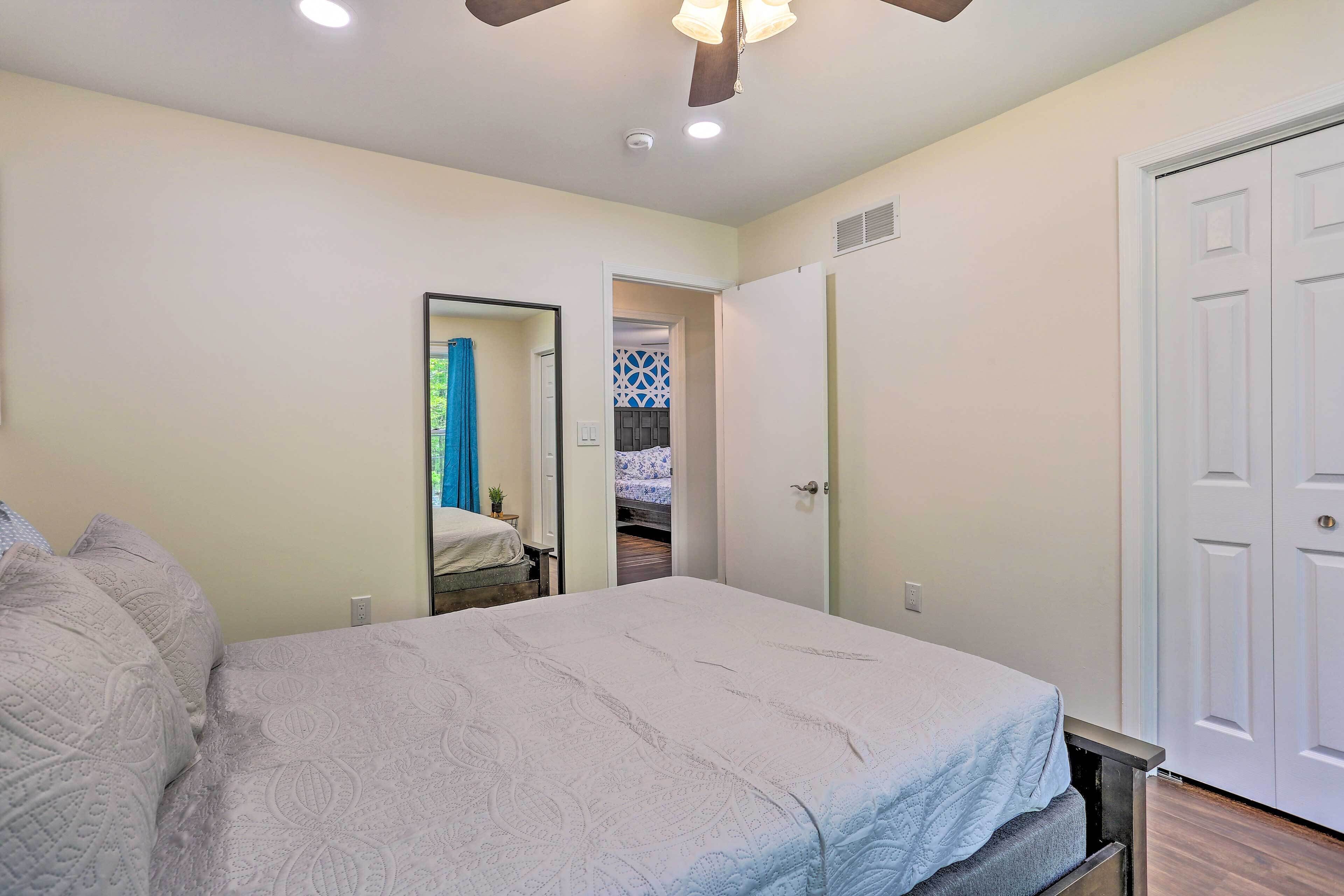 Une chambre à coucher avec un lit, un ventilateur de plafond et une porte donnant sur une salle de bain.