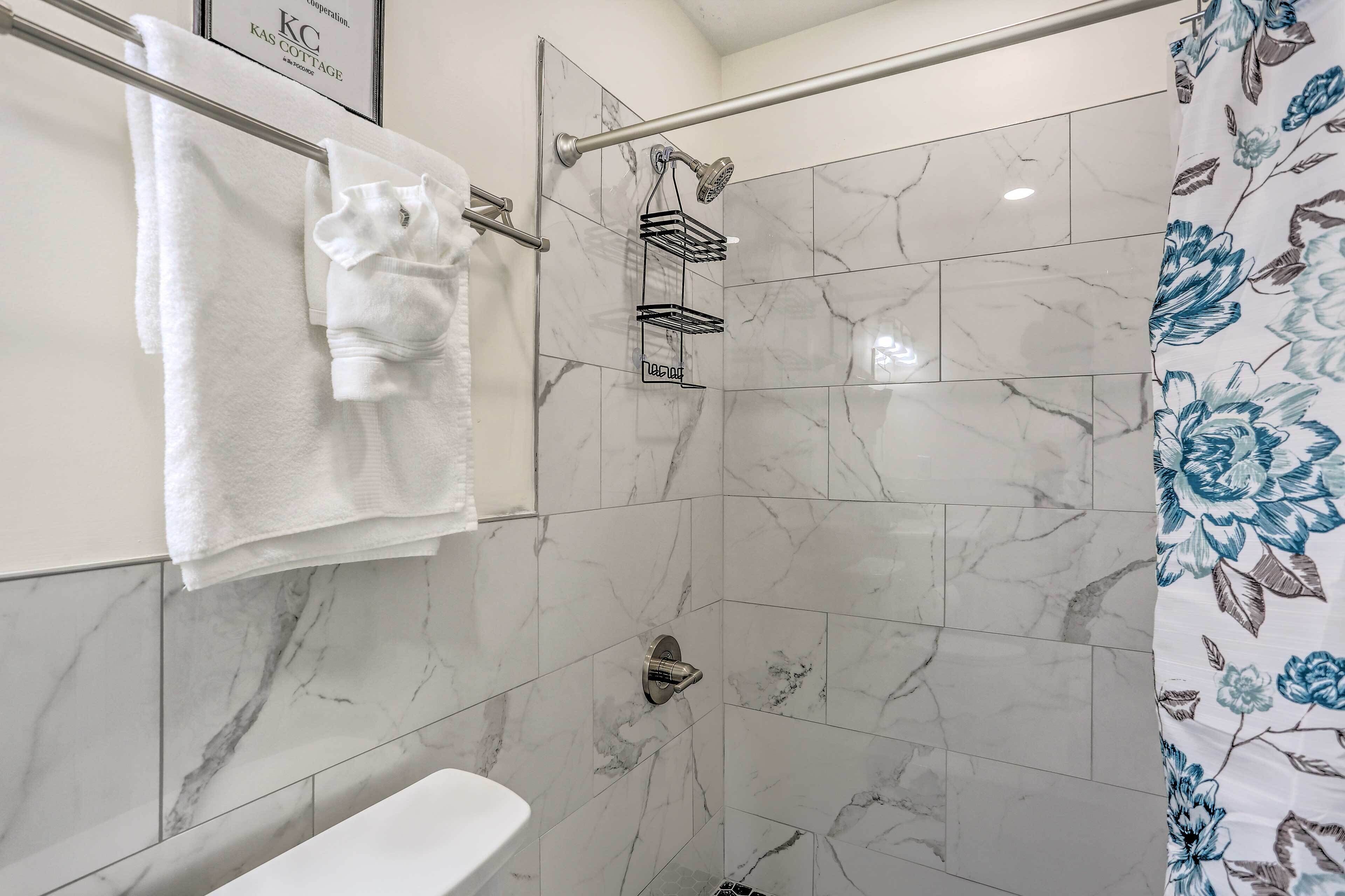 Une salle de bain avec douche, toilettes et porte-serviettes.