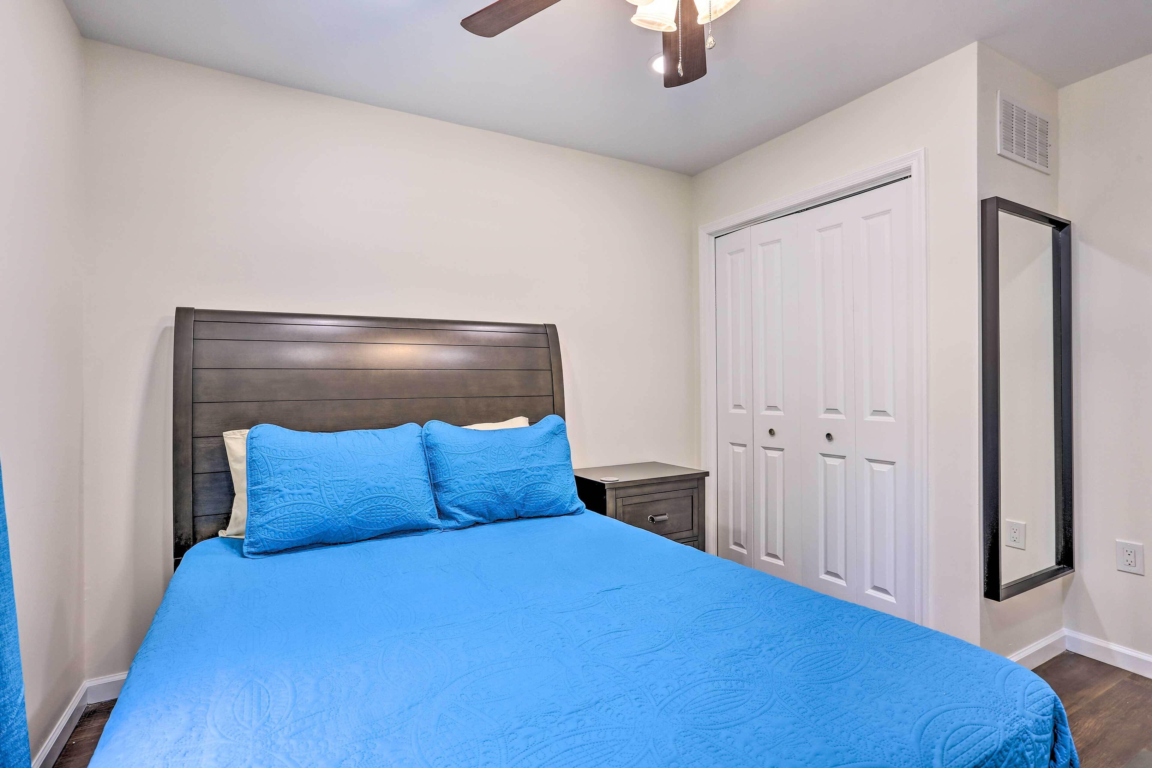 Une chambre à coucher comprenant un lit, une table de chevet, une armoire et un ventilateur de plafond.