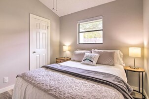 Un dormitorio con cama, dos mesitas de noche con lámparas, una ventana y una puerta.