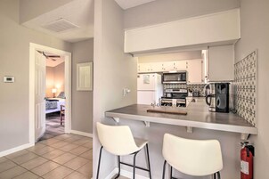 Una cocina compacta con barra, armarios blancos y microondas.