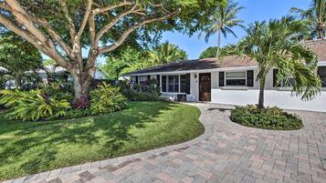 A house with a paved driveway, a large tree, and a well-maintained lawn.