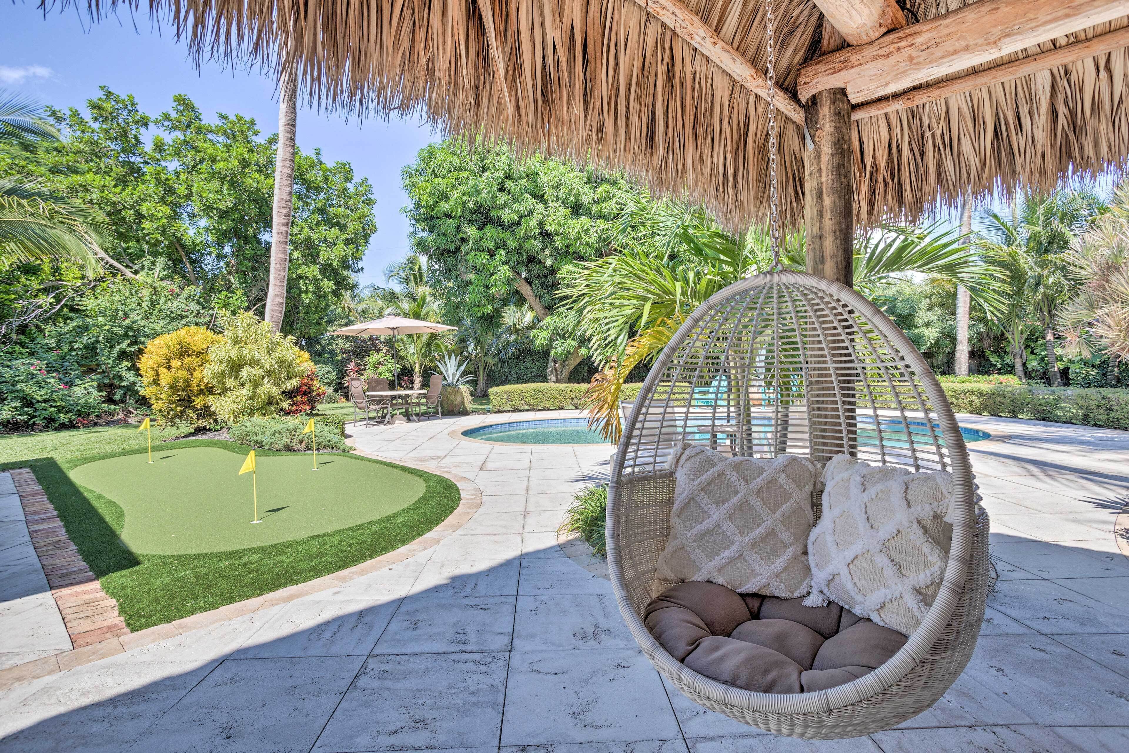 A hanging chair with cushions, a small pool, and a well-maintained garden with a putting green.