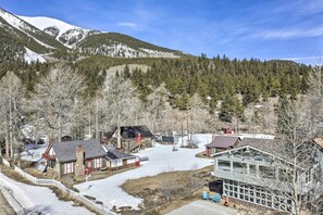 A cabin-style hotel with a snow-covered driveway, surrounded by forested mountains and clear skies. - Remodeled Lake Cabin, Stunning Mtn View, New Patio (Twin Lakes)