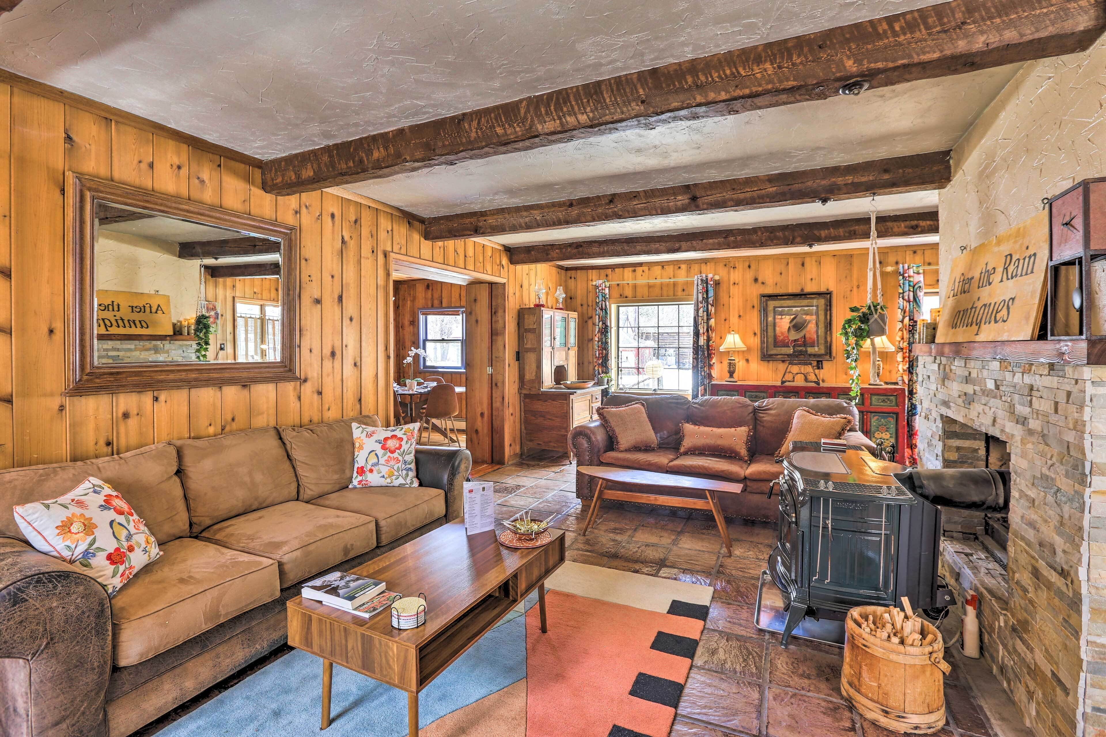 A cozy living room with wooden walls and a fireplace, furnished with sofas and a coffee table.