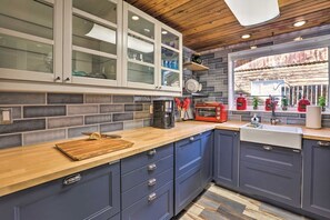 A modern kitchen with blue cabinets, a wooden countertop, a coffee maker, a toaster, and a window with a view of a rustic building. - Remodeled Lake Cabin, Stunning Mtn View, New Patio (Twin Lakes)
