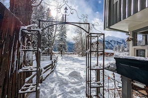 A snow-covered pathway leading to a metal gate with a mountain view.