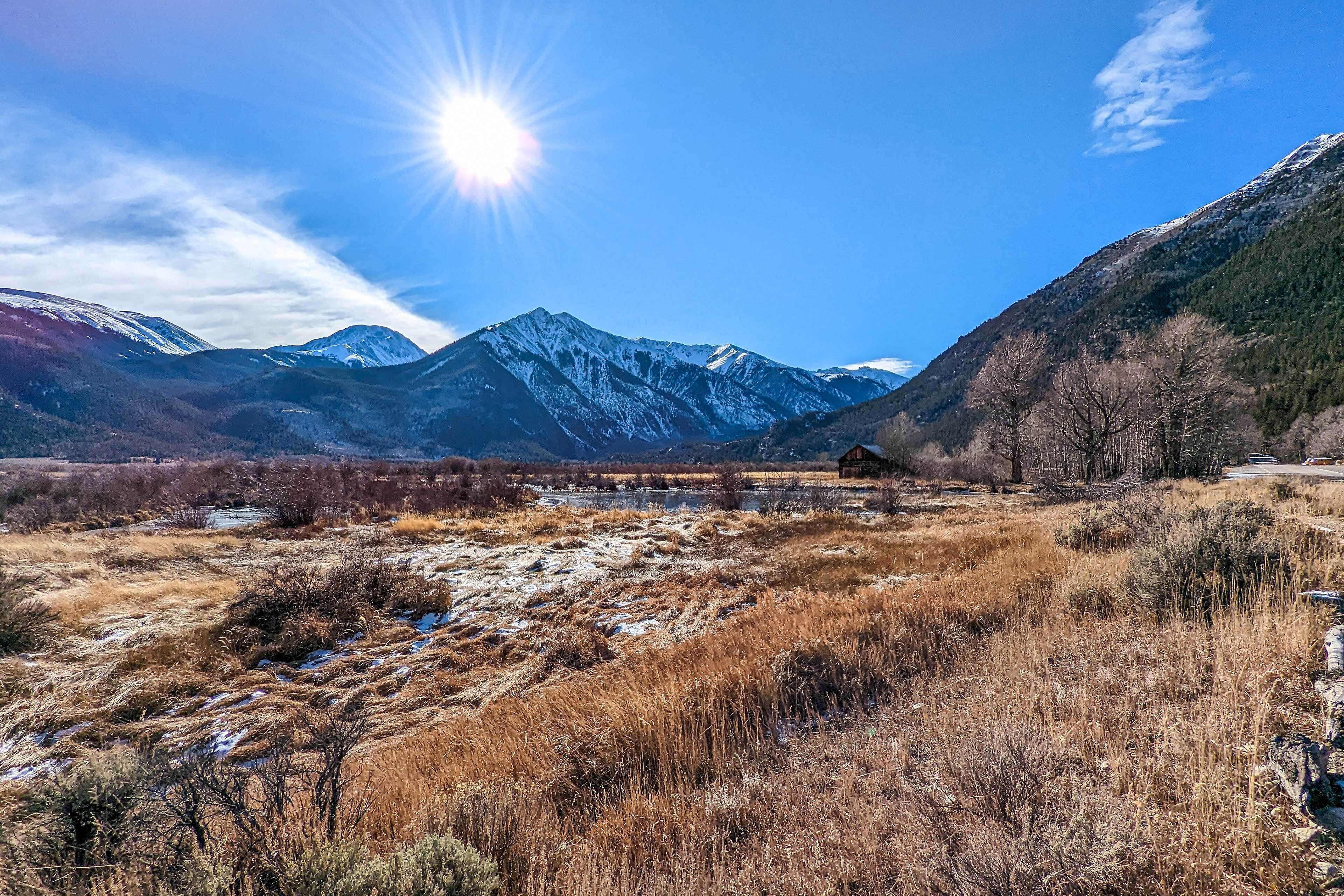 A mountainous landscape with a clear sky and a sun shining.