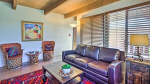 A living room with a leather sofa, two wooden chairs, a coffee table with a plant, and a patterned rug. - Traditional-style Adobe Casita - Walk to Dtwn (Santa Fe)