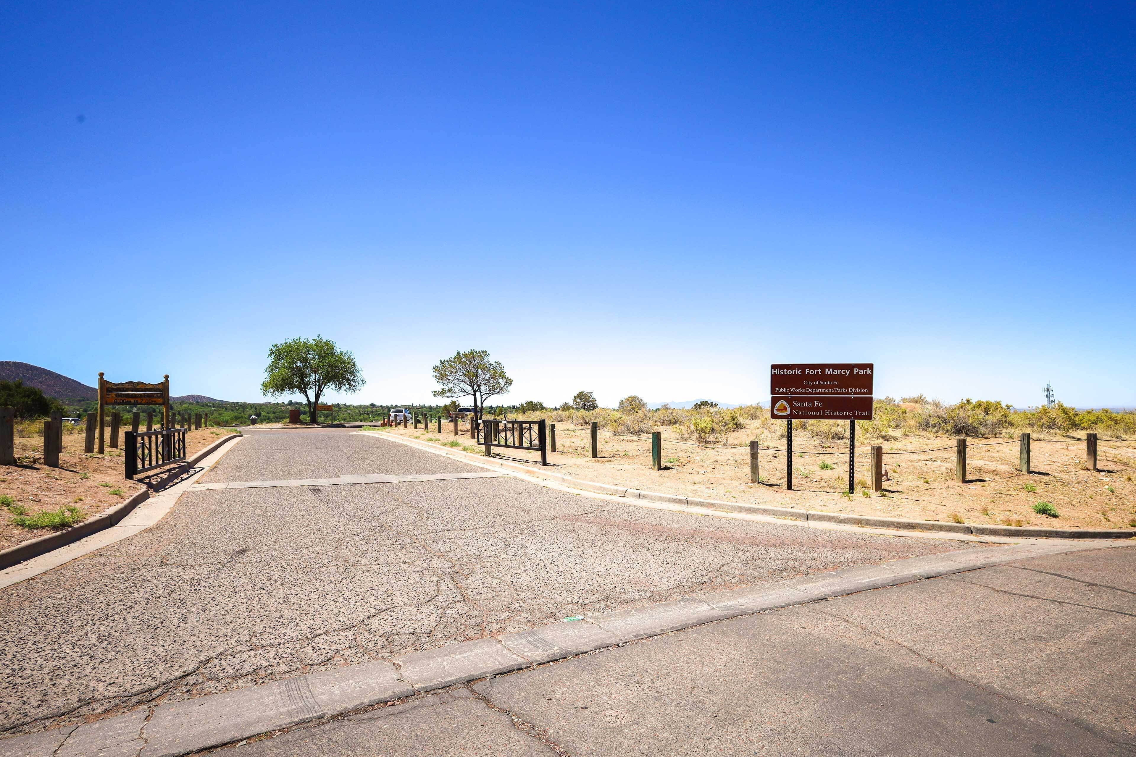 Una carretera pavimentada que conduce a un sitio histórico, con un letrero que indica el Sendero Histórico de Santa Fe.
