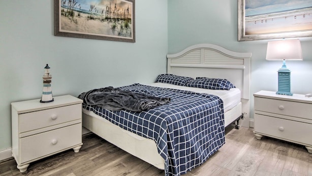 Una camera da letto con un letto, due comodini, una lampada e due quadri appesi al muro.