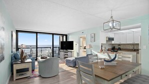 Un soggiorno moderno con una grande TV, un'area relax e vista sull'oceano.