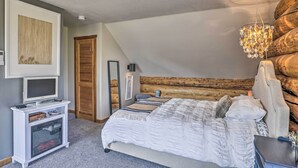 A bedroom with a large bed, a television on a stand, a fireplace, and a wooden log wall. - Fraser Couple's Hideaway w/ Indian Peaks View (Fraser)