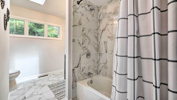 Een badkamer met een bad, een douche en een toilet.