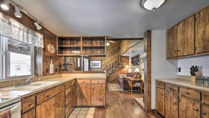 A kitchen with wooden cabinets, a large island, and a dining area with a couch and table. - Cozy Log Cabin Escape In the Heart of Creede! (Creede)