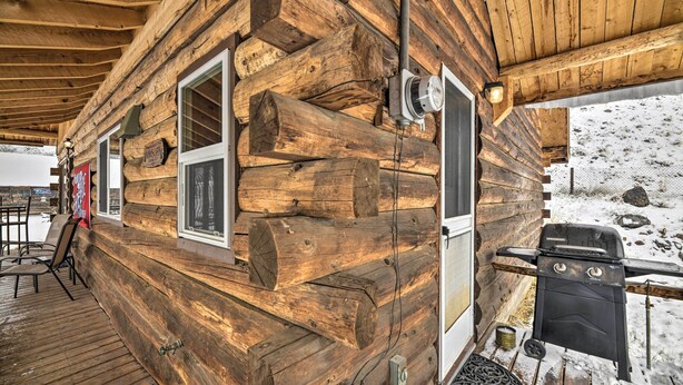 A log cabin with a wooden deck, a grill, and a view of a snowy landscape. - Cozy Log Cabin Escape In the Heart of Creede! (Creede)