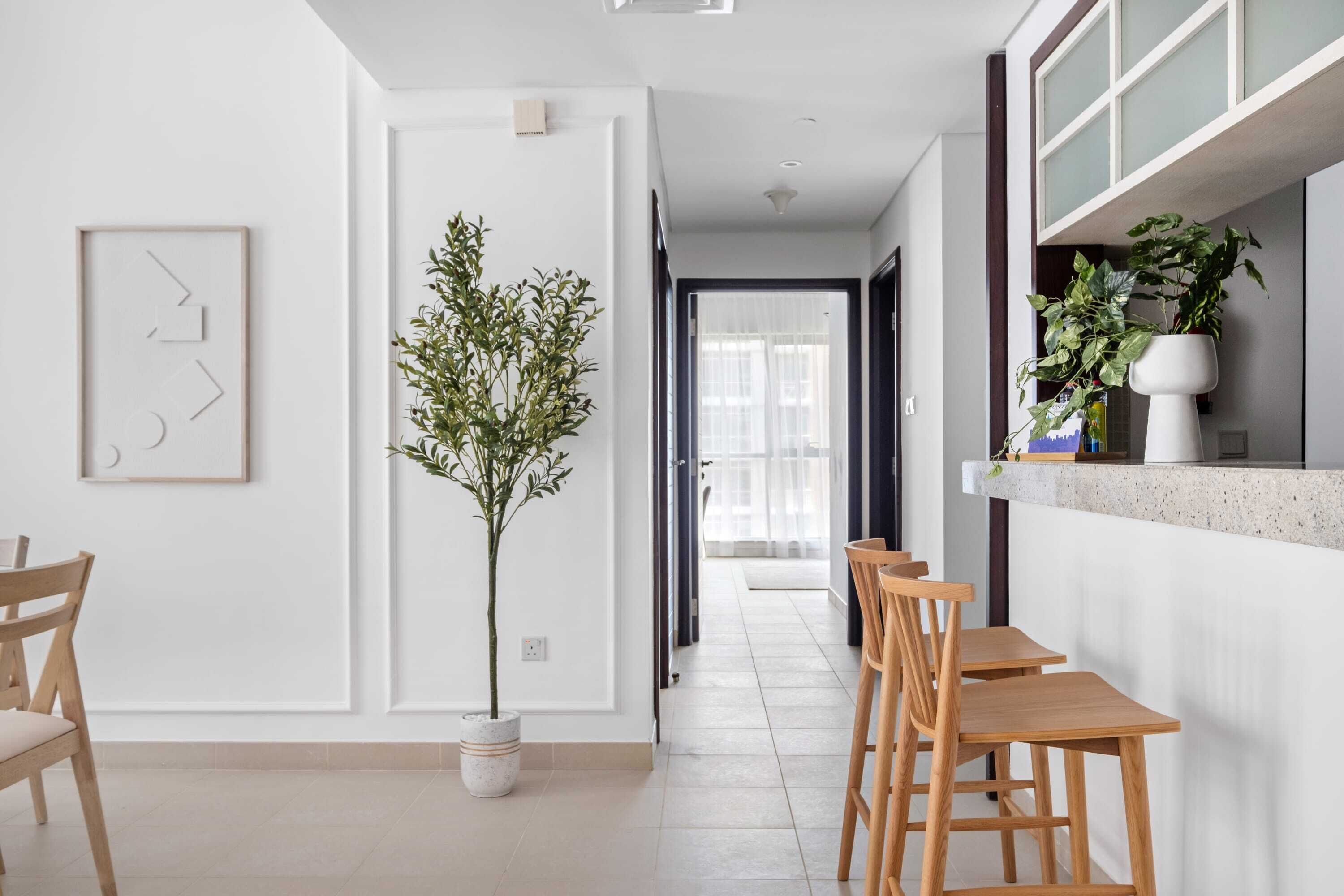 Une cuisine moderne avec un îlot central, des chaises en bois et une plante en pot.