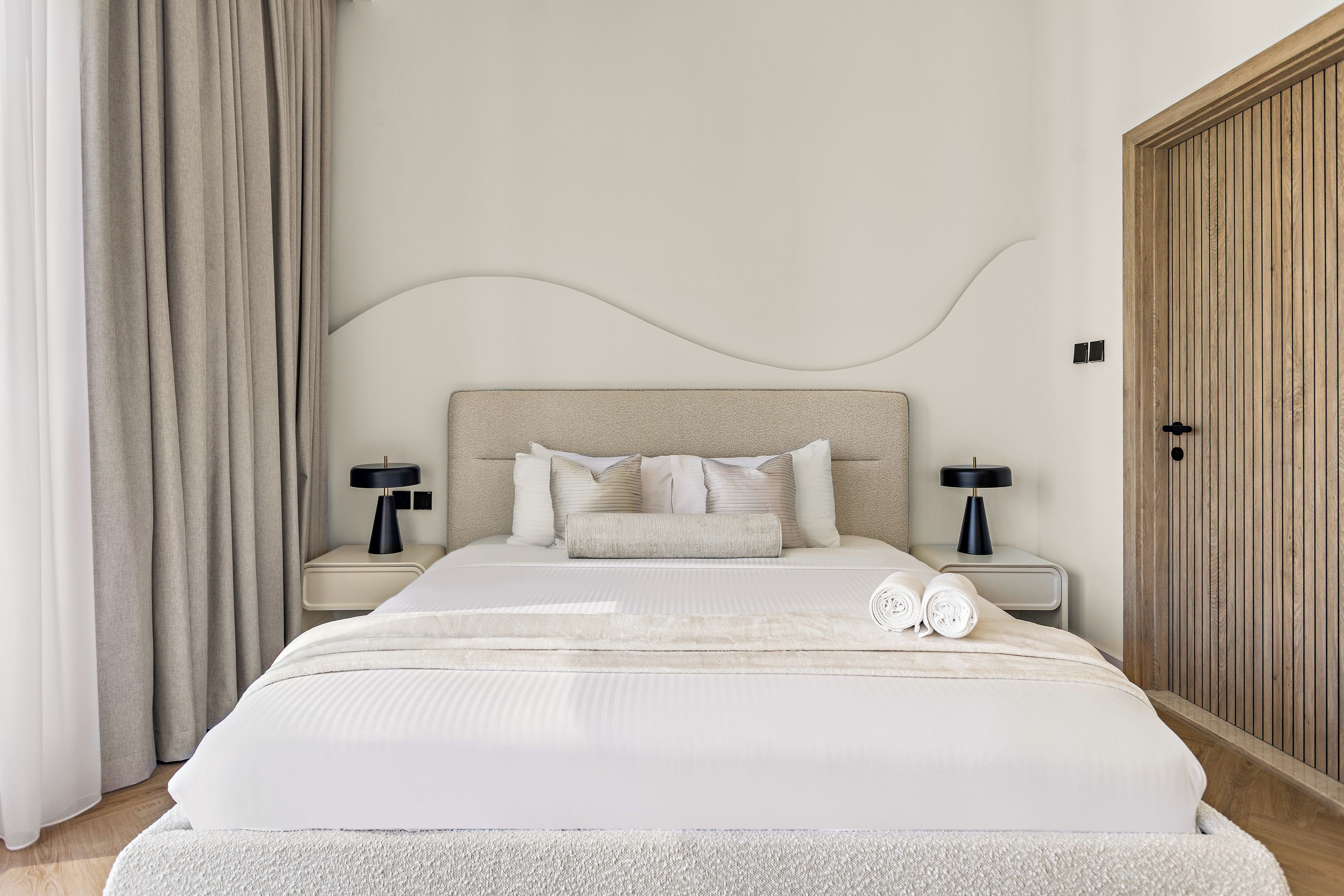 Een moderne slaapkamer met een groot bed, twee nachtkastjes, een hoofdbord en een kledingkast.