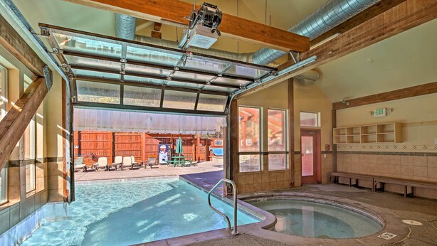 Un área de piscina con agua cristalina, un jacuzzi y una entrada techada.