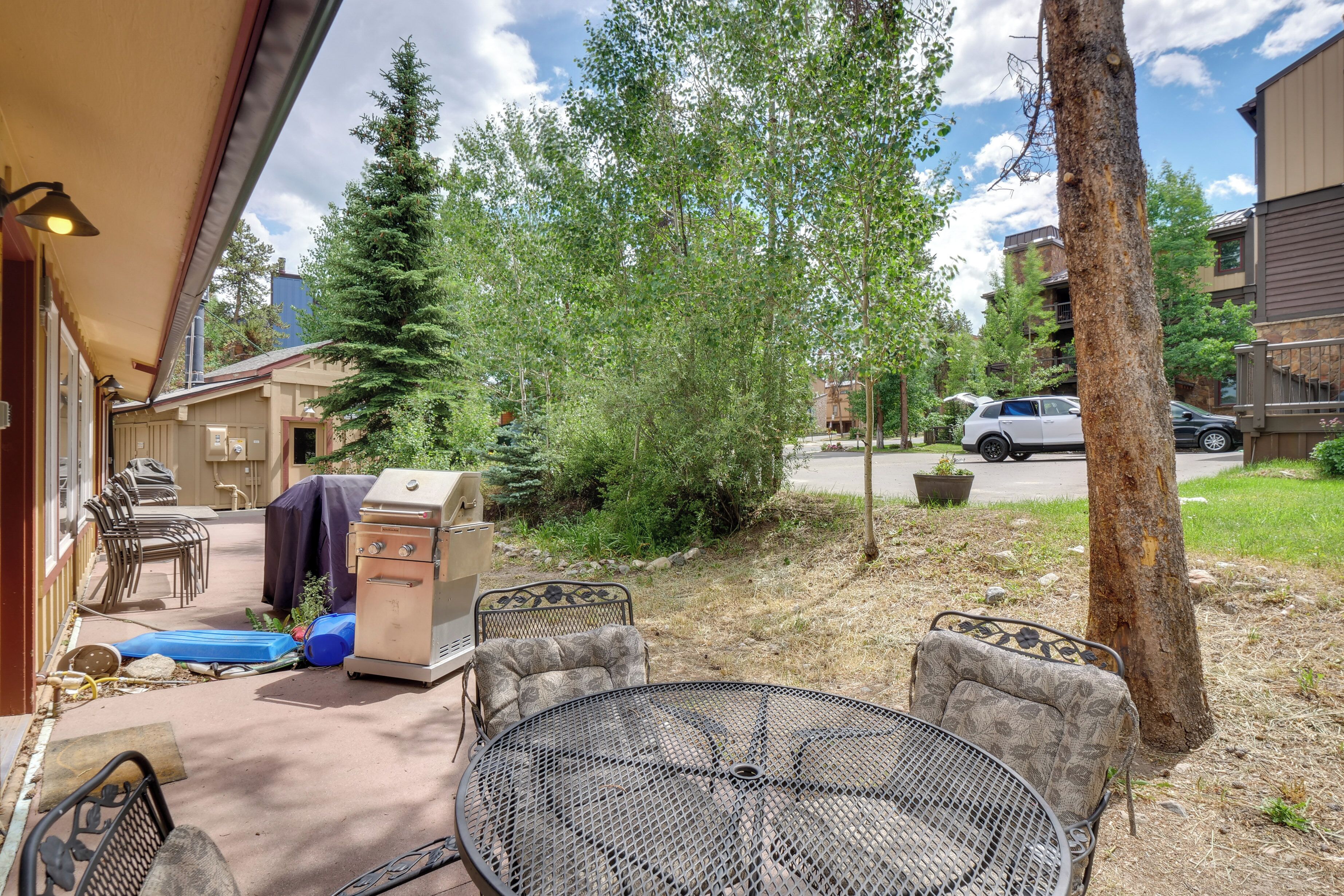 An outdoor patio with a grill, chairs, and a table.
