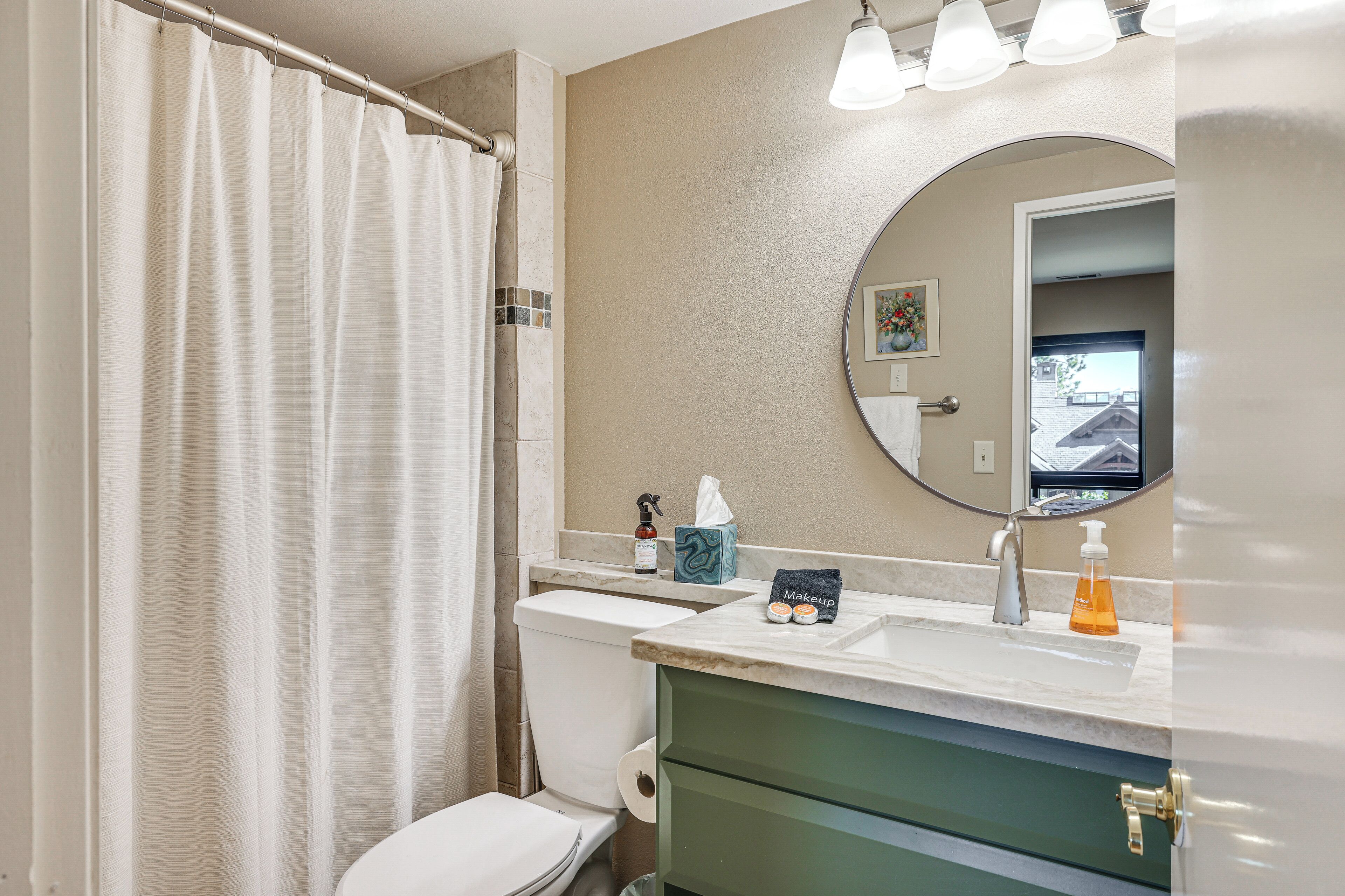 A bathroom with a toilet, sink, and shower curtain.