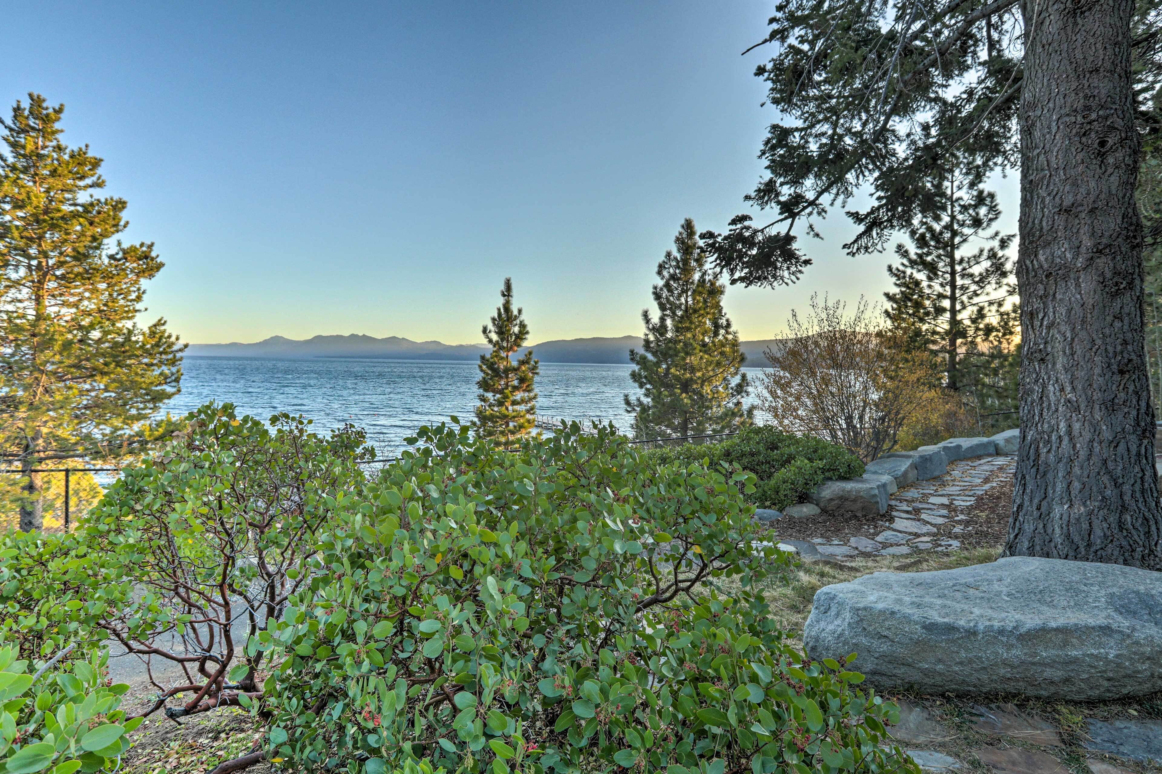 A natural landscape with a stone pathway leading to a body of water, surrounded by trees and rocks.