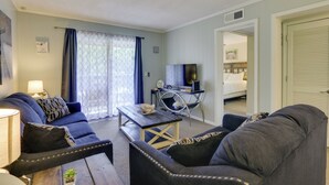 Una sala de estar con sofá, sillones, una mesa de centro y un televisor.