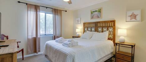 A bedroom with a bed, bedside tables, a ceiling fan, and a window with curtains.