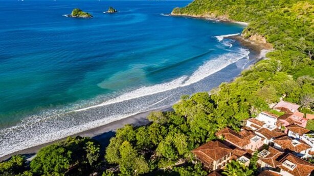 A coastal area with a beach, a few small islands, and a cluster of houses with red-tiled roofs. - Las Catalinas - Studio Cazenovia Centrally Located Short Walk to Beach (Tempate)