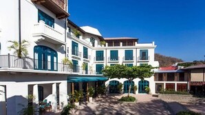 A multi-story hotel with a courtyard, balconies, and outdoor seating areas. - Las Catalinas - Studio Cazenovia Centrally Located Short Walk to Beach (Tempate)