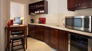 A modern kitchen with dark wooden cabinets, a stainless steel microwave, and a built-in oven. - Las Catalinas - Studio Cazenovia Centrally Located Short Walk to Beach (Tempate)