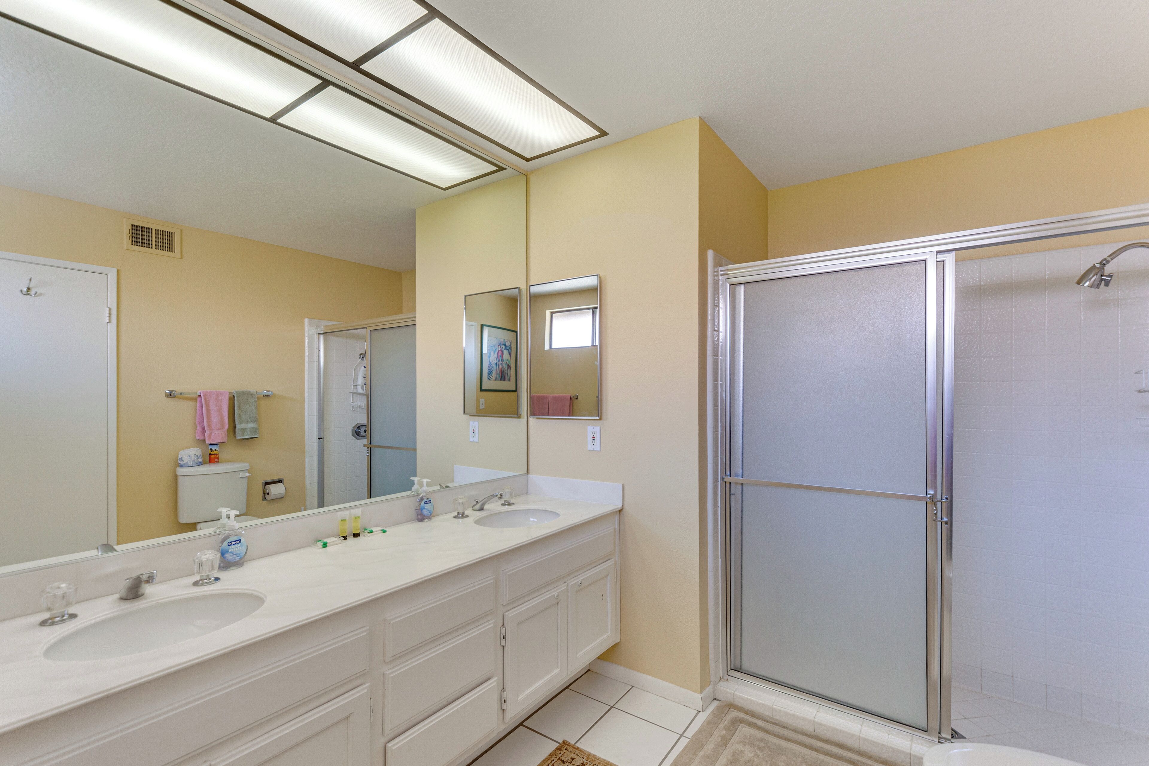 Un bagno con due lavandini, uno specchio grande e una cabina doccia in vetro.