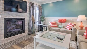 Ein Wohnzimmer mit Kamin, einem darüber montierten Fernseher und einer türkisblauen Wand.