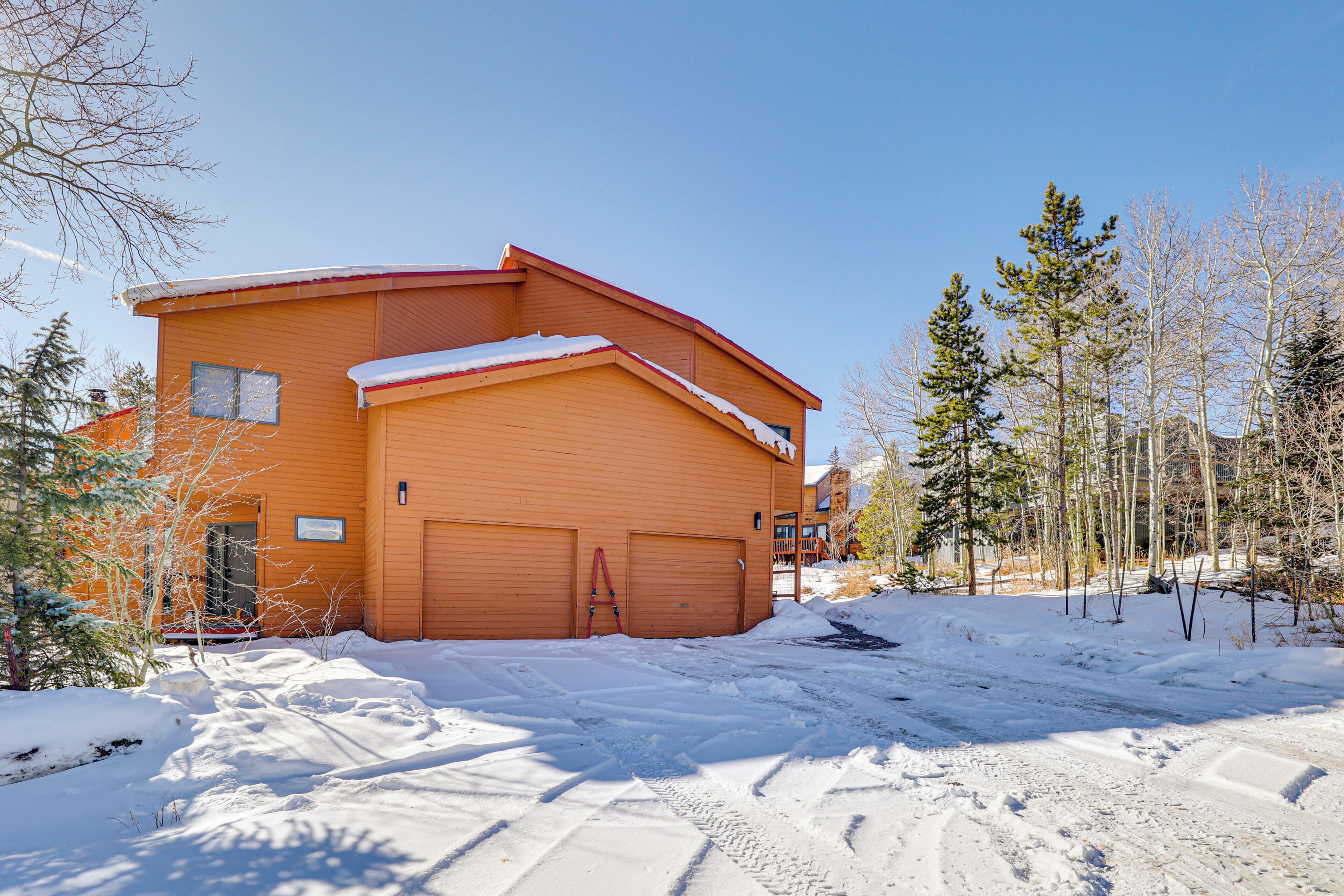 A two-story building with a red roof and wooden siding, surrounded by snow-covered ground and trees.