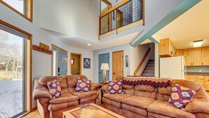 A spacious living room with a large brown leather sofa set, a wooden coffee table, and a view of the outside through large windows. - 10 Mi to Keystone Resort: Cabin w/ Private Hot Tub (Silverthorne)