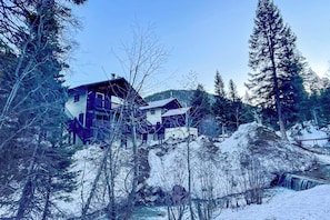 A two-story lodge with a balcony, surrounded by snow-covered trees and a clear sky. - Cozy Streamside Studio - 2 Mi to Taos Ski Resort! (Taos Ski Valley)