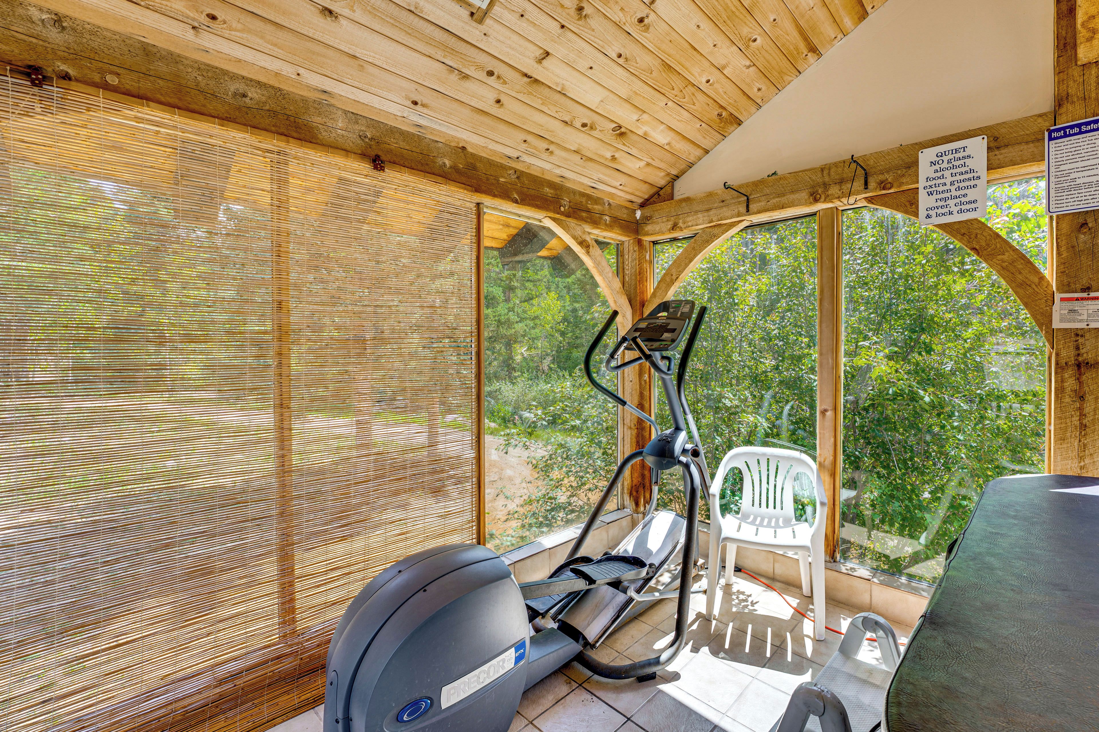 Un gimnasio al aire libre techado con equipo de ejercicios, incluyendo una bicicleta estática y una caminadora, y una silla.