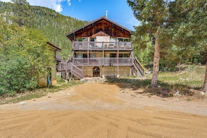 A two-story wooden lodge with a balcony, surrounded by forest. - Cozy Streamside Studio - 2 Mi to Taos Ski Resort! (Taos Ski Valley)