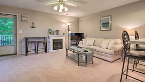 A living room with a fireplace, a sofa, a coffee table, a TV, and a ceiling fan.