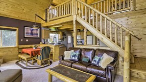 A cozy cabin interior with a wooden staircase, a dining area, and a living room furnished with leather sofas and a coffee table. - Secluded Fairplay Home w/ Hot Tub & Mountain Views (Fairplay)